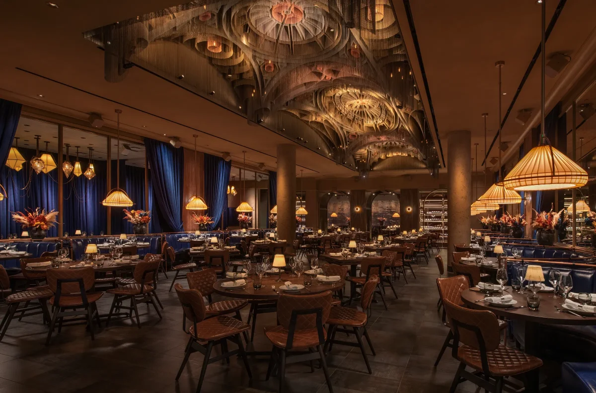 Main dining room at CATCH Las Vegas with blue velvet curtains, woven sculptural ceiling, and lamp-lit tables set for dinner