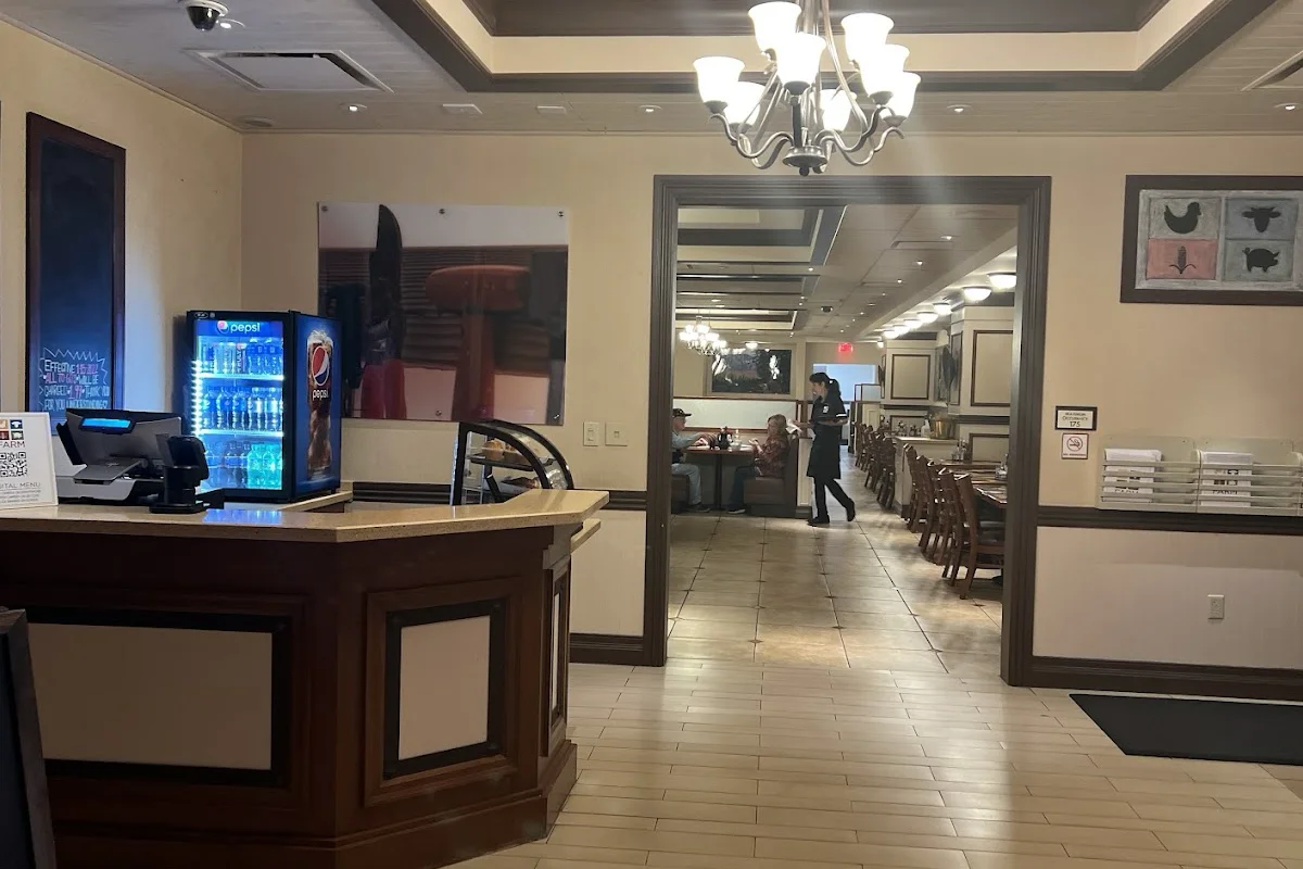FARM dining room interior with a host stand, drink cooler, chandeliers, and a tiled floor leading to tables at Aliante