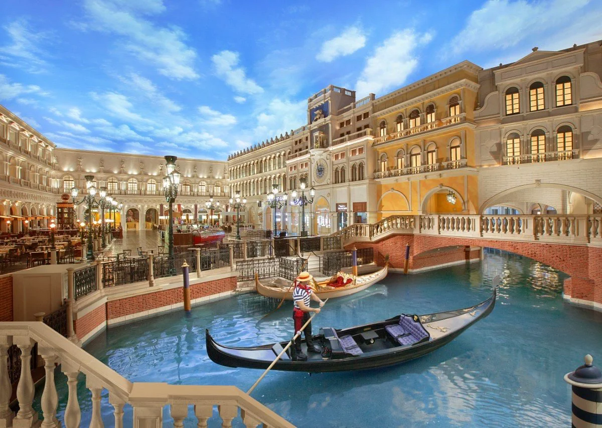 Gondola gliding along the indoor canal beneath a painted blue-sky ceiling at Grand Canal Shoppes