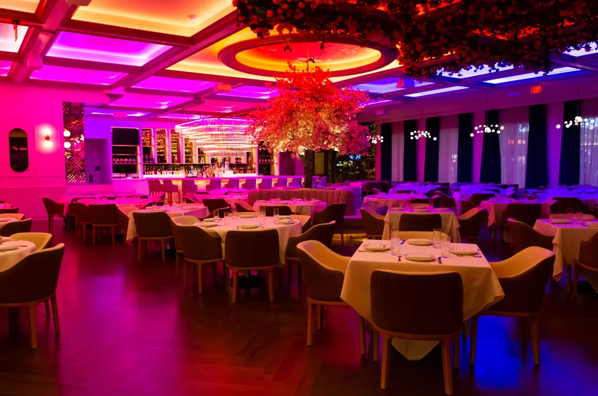 Pink-lit dining room with a cherry blossom centerpiece and a bar at a Grand Canal Shoppes restaurant