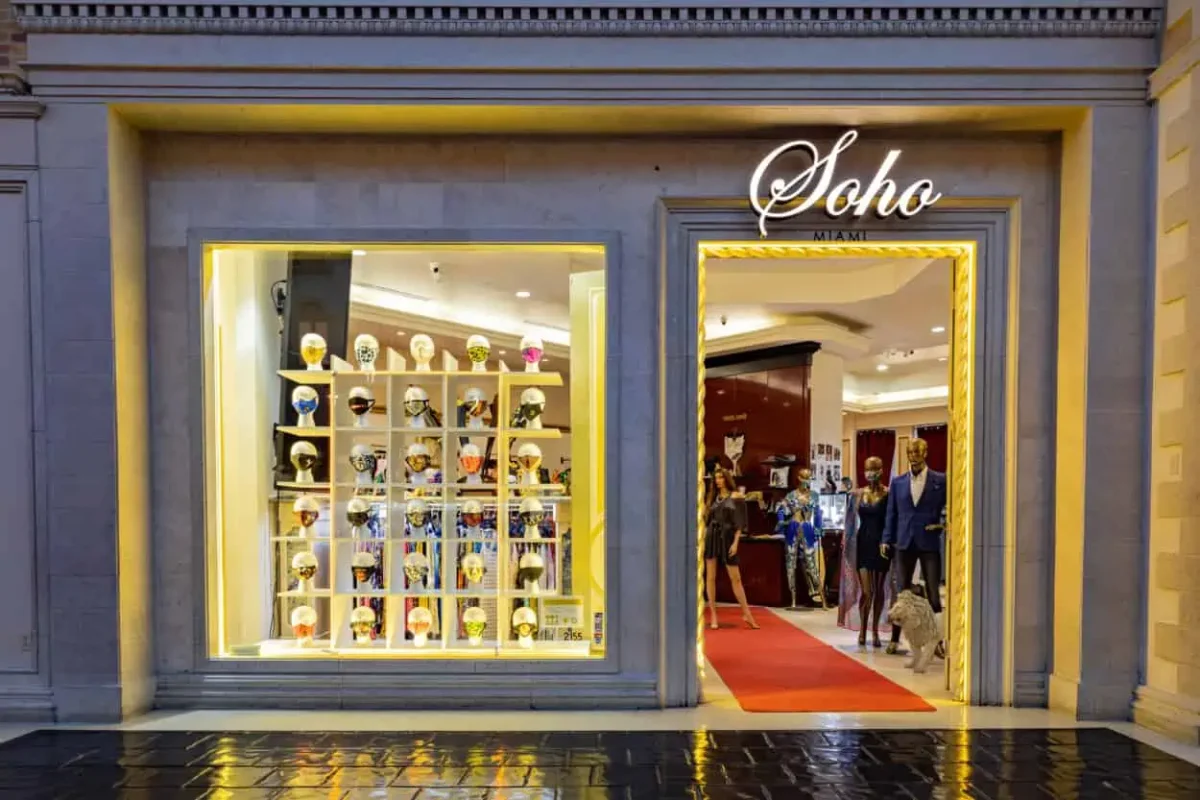 Illuminated Soho Miami storefront with a decorated-mask window display at Grand Canal Shoppes
