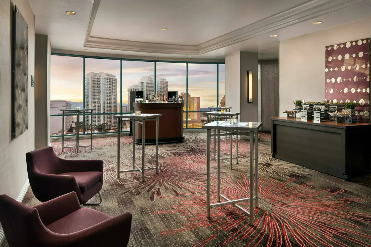Top-floor hospitality suite with a bar, cocktail tables and sunset city views