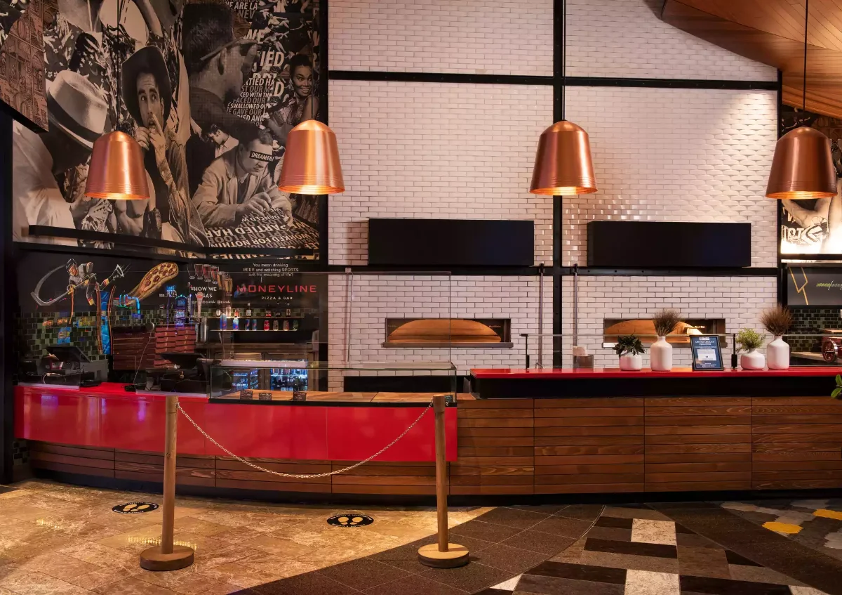 Craft beer and bar seating beneath game-day screens at Moneyline ARIA