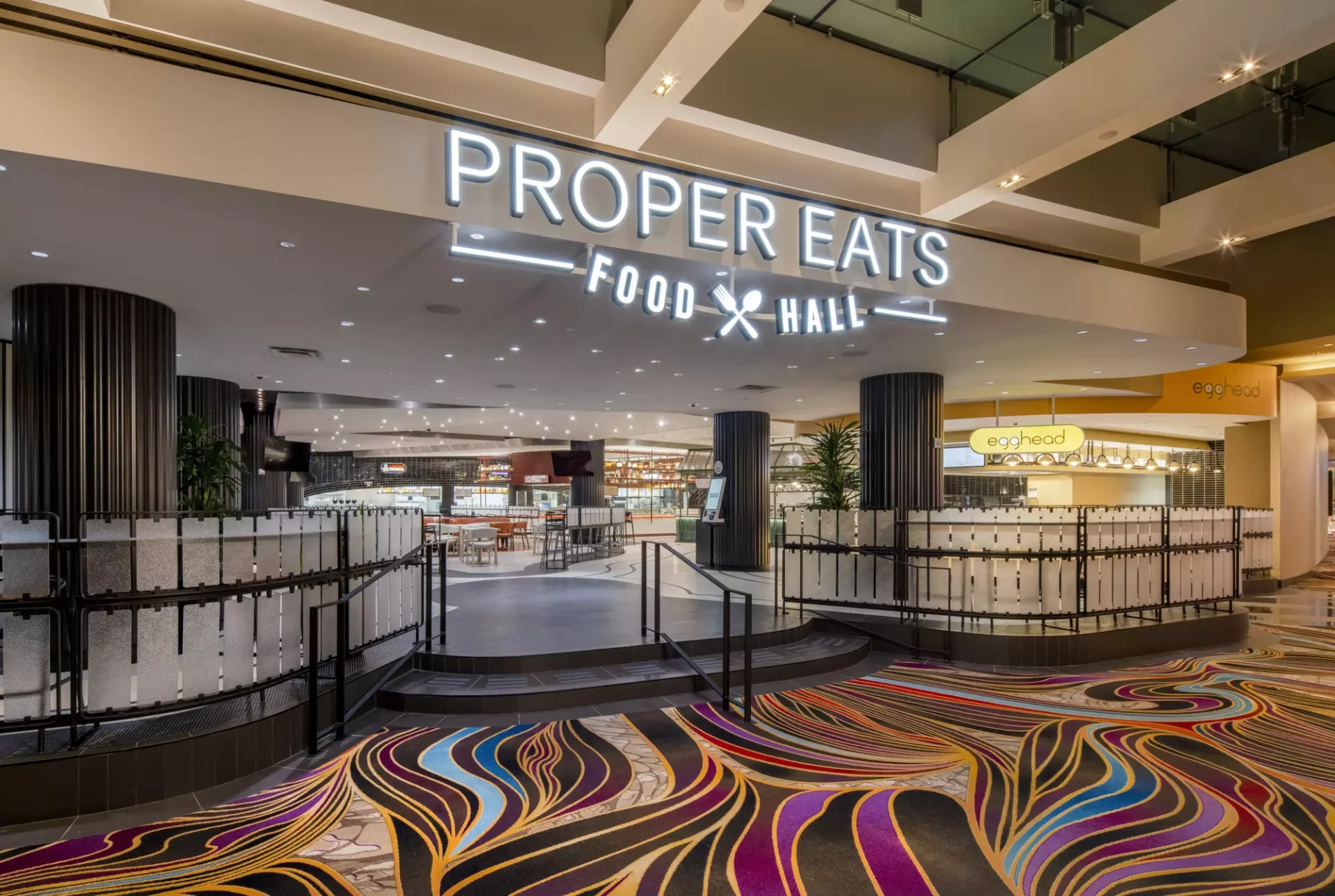 Illuminated Proper Eats Food Hall entrance sign above colorful swirled carpeting at ARIA Las Vegas