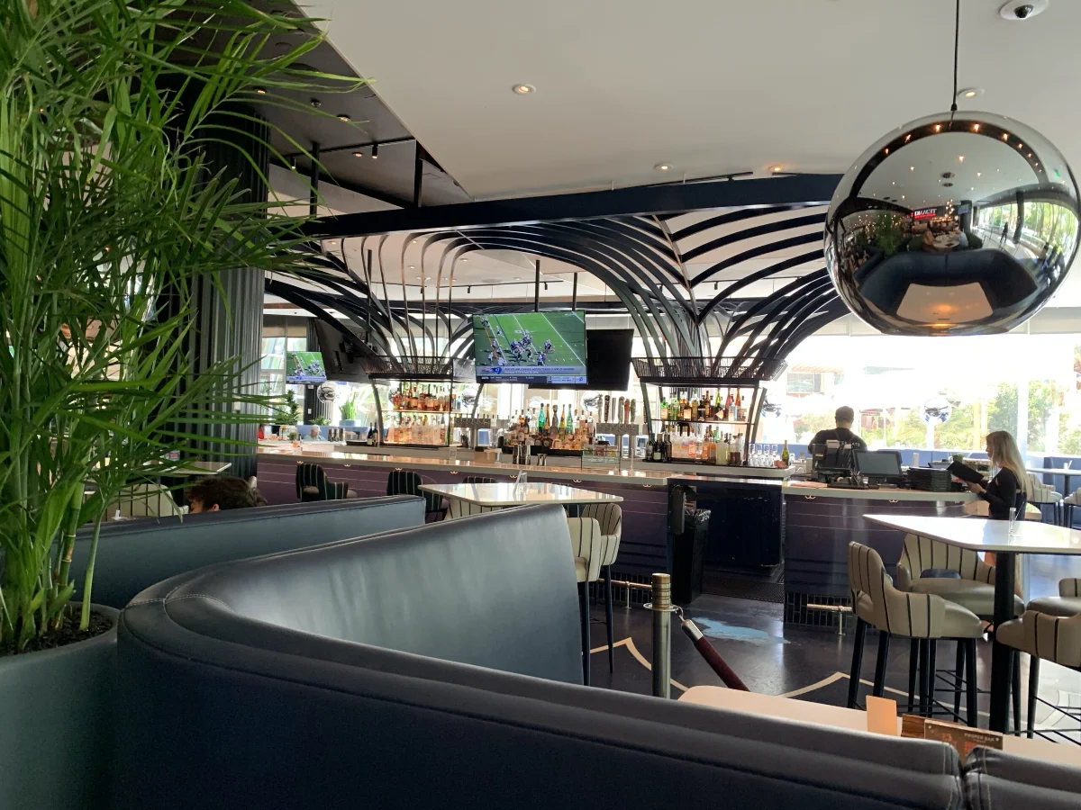 Curved lounge seating and bar beneath a sculptural ceiling at Proper Eats Food Hall ARIA