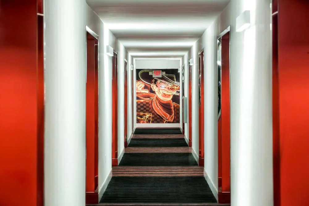 Guest room hallway with red walls and Vegas Vic neon art at The D