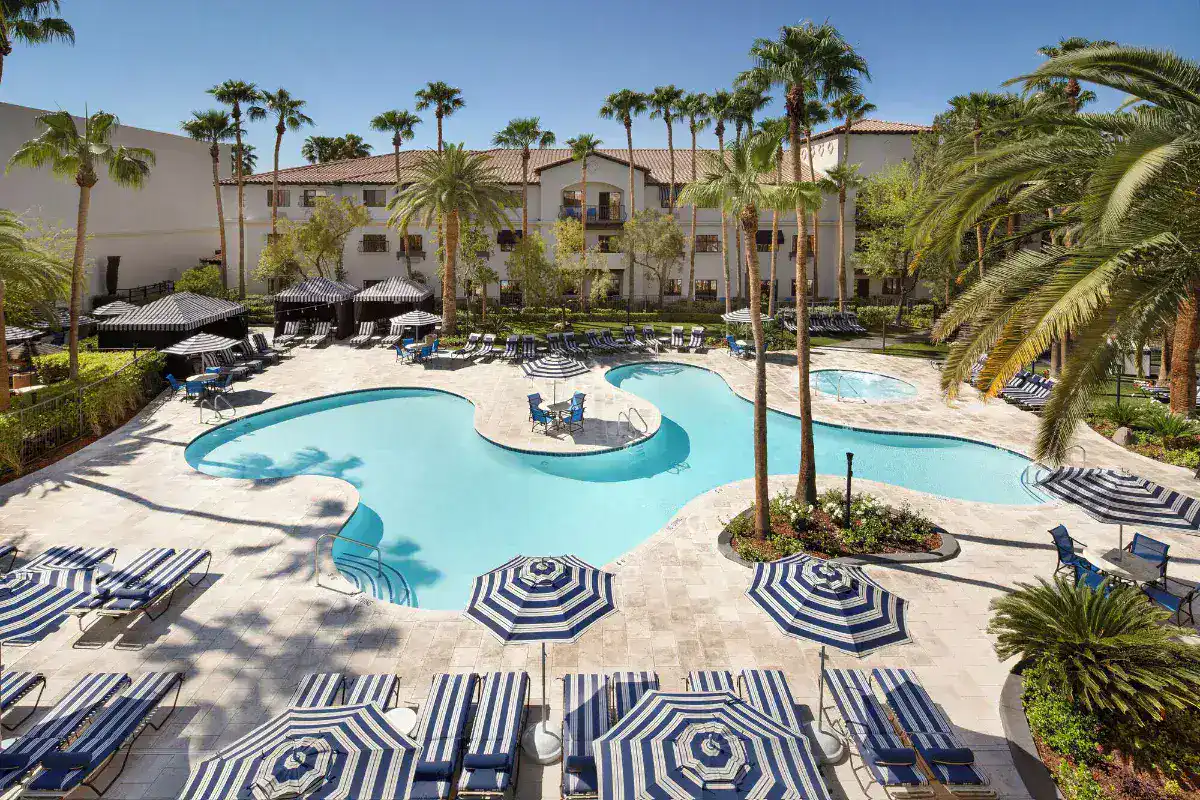 Pool with striped umbrellas and palm trees at Tuscany Suites