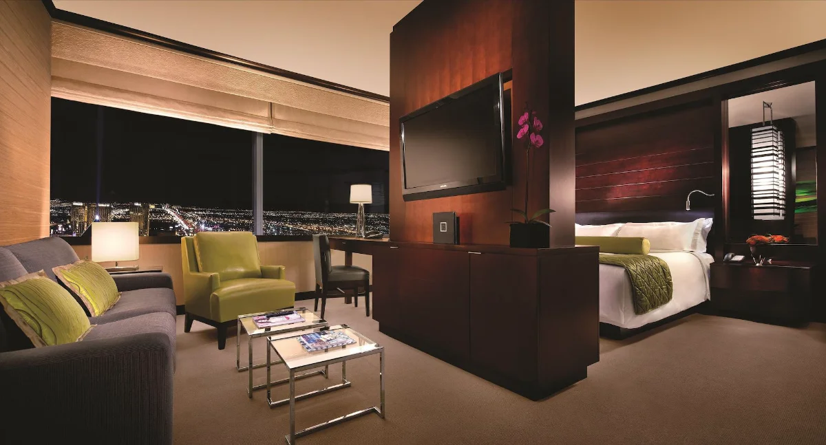 Studio suite with green accent chairs and city view at Vdara