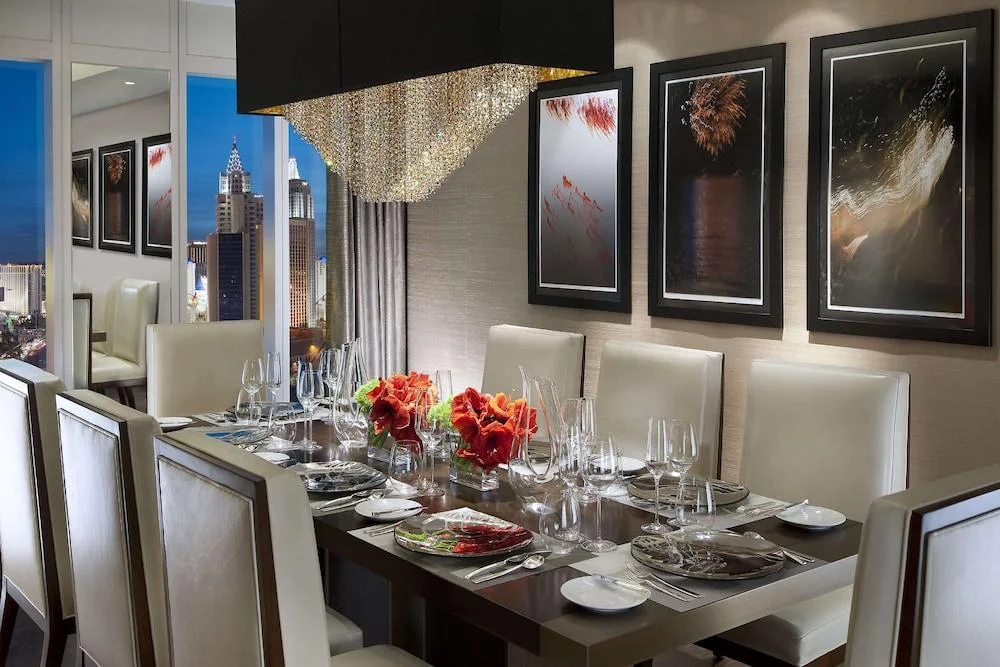 Suite dining room with crystal chandelier and Strip views at Waldorf Astoria